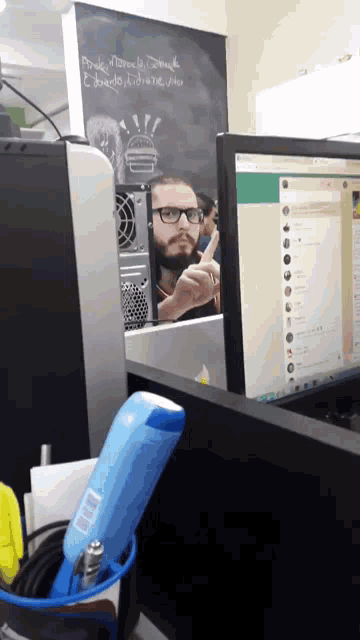 a man sitting in front of a computer with a sign on the wall that says marcelo