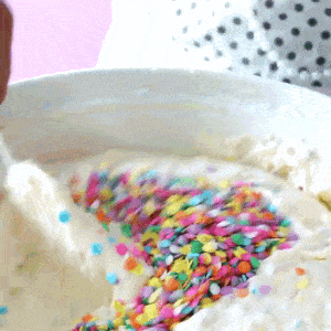 sprinkles are being added to a bowl of frosting