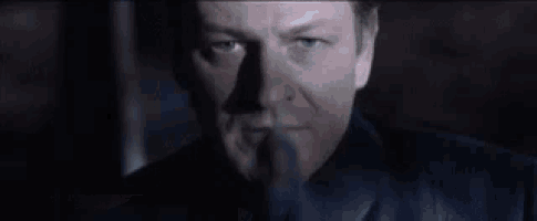 a man in a black suit is holding a book in his hand in a dark room .