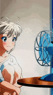 a girl is sitting in front of a blue fan on a table