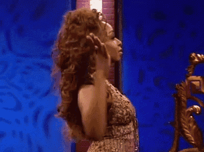 a woman in a leopard print dress is standing in front of a mirror and holding her hair .