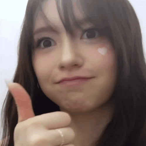 a close up of a woman giving a thumbs up sign