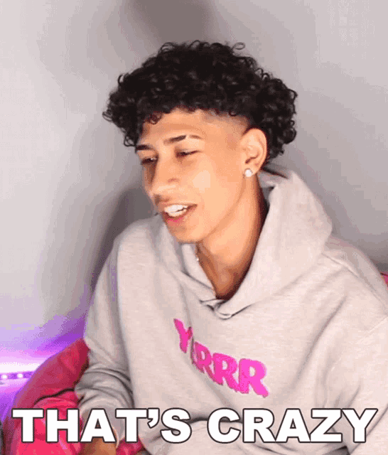 a young man with curly hair is wearing a hoodie that says yrrr that 's crazy