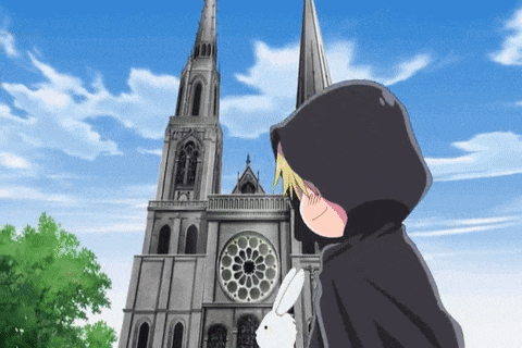 a person in a hooded cape stands in front of a large building