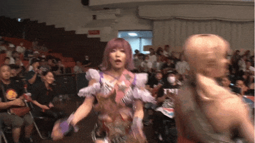 a woman with pink hair is standing next to a man in a wrestling ring .