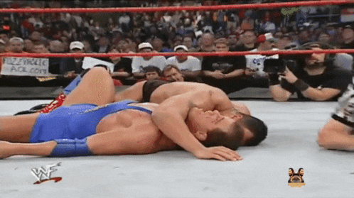 two men are wrestling in a wrestling ring with a sign that says fuzzyholic .