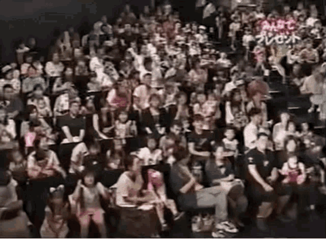 a large group of people are sitting in a theater watching a show .