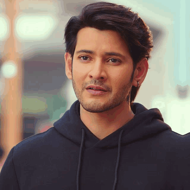 a man in a black hoodie looks at the camera