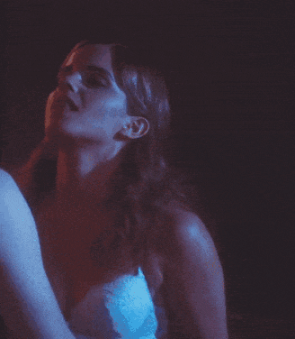 a woman in a white bra is standing next to a man in a blue light