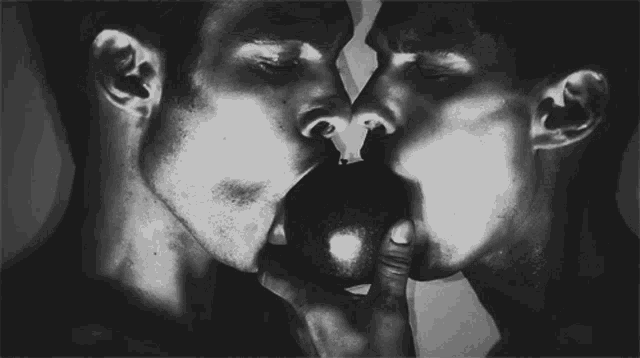 two men are kissing each other and one is holding an apple in his hand