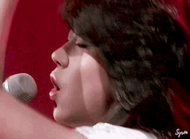 a close up of a woman singing into a microphone with syria written on the bottom