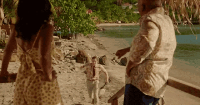 a group of people are walking on a beach and one of them is holding a machete