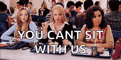 a group of girls are sitting at a table in a cafeteria eating food .