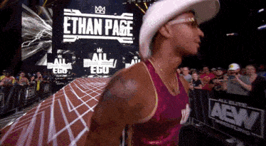 a man wearing a cowboy hat and glasses is walking in front of a sign that says ethan page