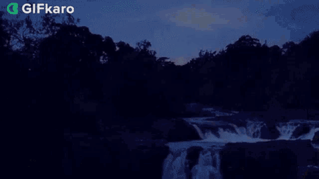 a waterfall in the middle of a forest with the sun shining through the trees .