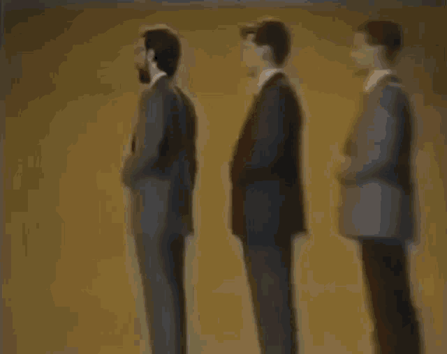 three men in suits and ties are standing next to each other .