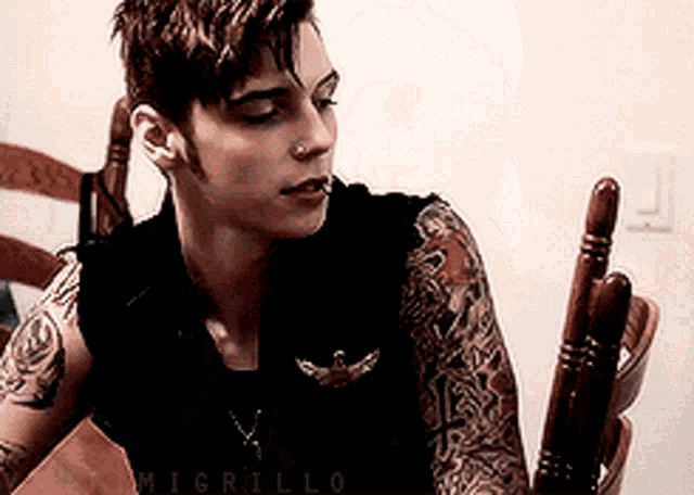 a man with a lot of tattoos on his arms is sitting at a table .
