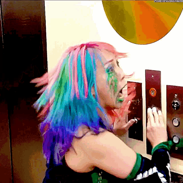 a woman with rainbow hair and green paint on her face is pressing an elevator button