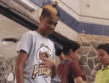 a boy with a mohawk and a pringles shirt is standing in a room with other boys .