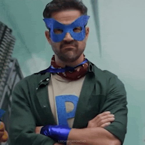 a man wearing a blue mask and a green jacket with his arms crossed .