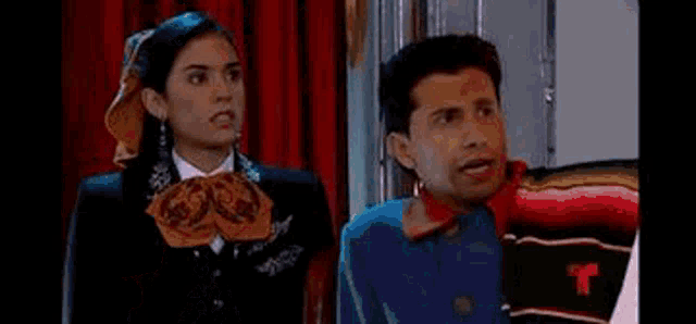 a man in a striped shirt is standing next to another man in front of a picture of a woman .