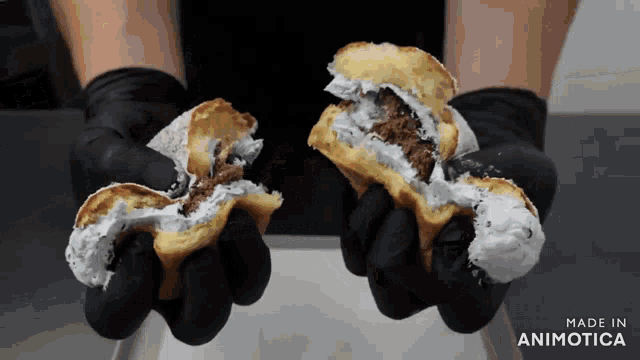 a person wearing black gloves is holding two sandwiches that are made in animotica