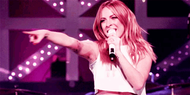a woman singing into a microphone while pointing