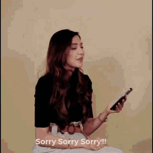 a woman is holding a cell phone and says sorry sorry sorry !!!