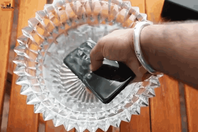 a person is holding a cell phone in an ashtray that says techna