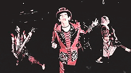 a woman wearing a top hat and a red jacket is standing in the dark .