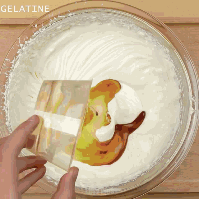 a bowl of whipped cream with a piece of gelatin being poured into it
