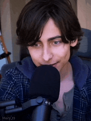 a young man is talking into a microphone and smiling .