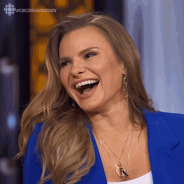 a woman in a blue jacket is laughing with the hashtag #cbcdragonsden behind her