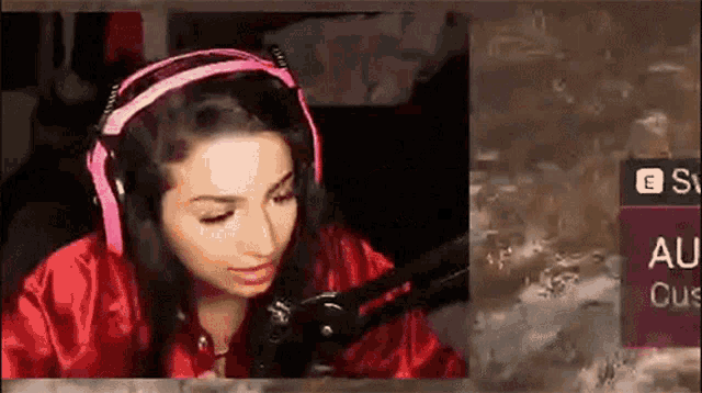 a woman wearing pink headphones is sitting in front of a microphone ..