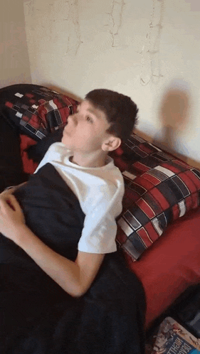 a boy is laying on a bed with a newspaper on the floor