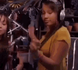 a woman wearing headphones stands in front of a microphone .