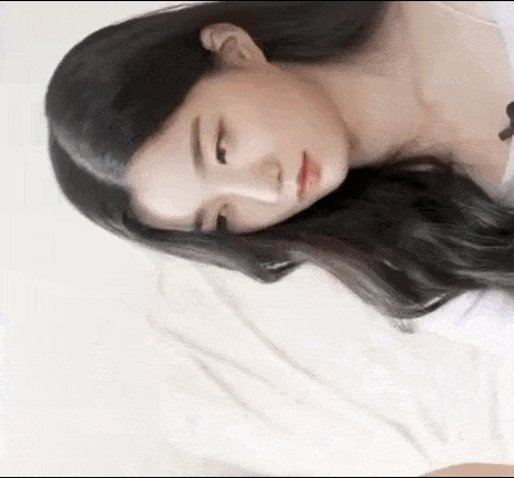 a close up of a woman laying on a bed with her head on a pillow .