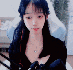 a girl with long black hair is sitting in front of a microphone .