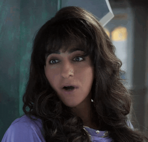 a woman with a surprised look on her face is wearing a purple shirt