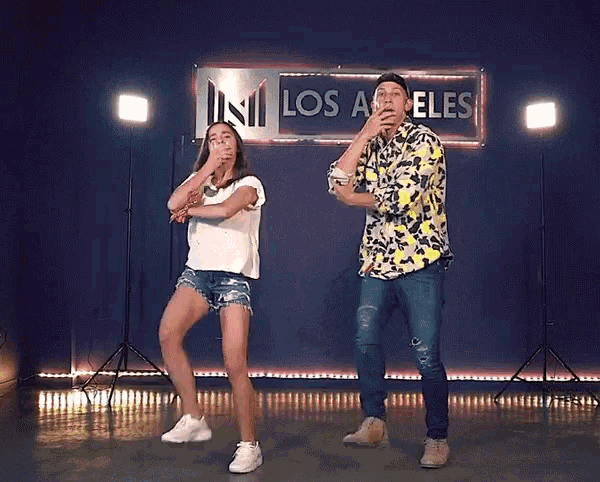 two people are dancing in front of a sign that says los angeles