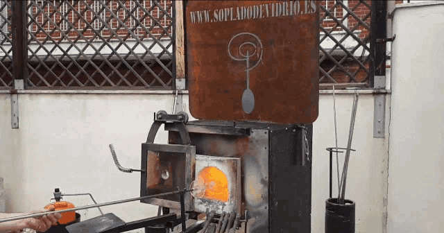 a sign that says www.soplaodenvidrio.es is behind a glass furnace