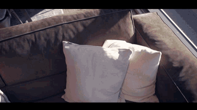 a couch with two pillows on it is sitting in front of a window
