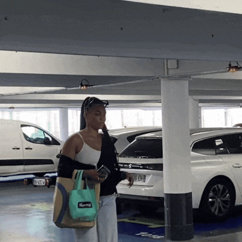 a woman walking in a parking garage holding a bag that says norma