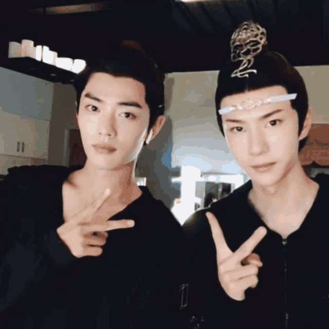 two young men are posing for a picture and one is wearing a crown