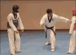 a group of people in karate uniforms are standing on a blue floor .