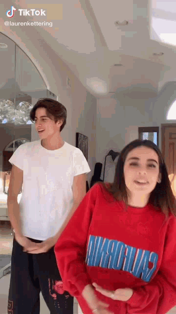 a boy and a girl are standing next to each other in a living room .