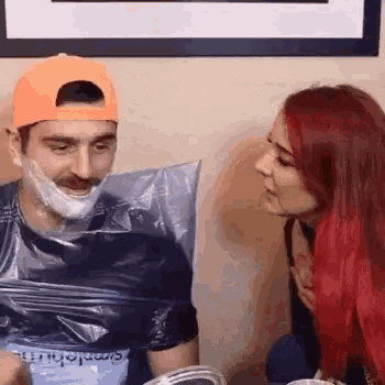 a woman is kissing a man who is wrapped in plastic .
