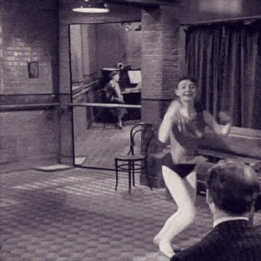 a black and white photo of a woman dancing in a room