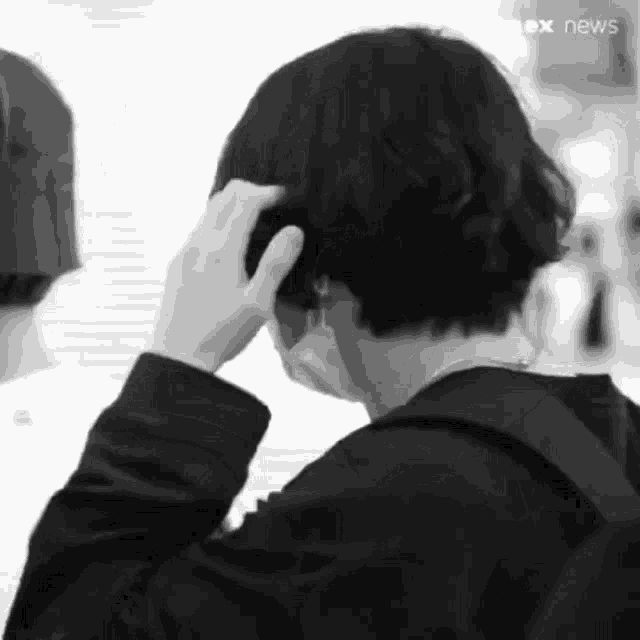 a black and white photo of a man touching his hair