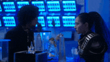a man and a woman are standing next to each other in a room with a lot of lights .